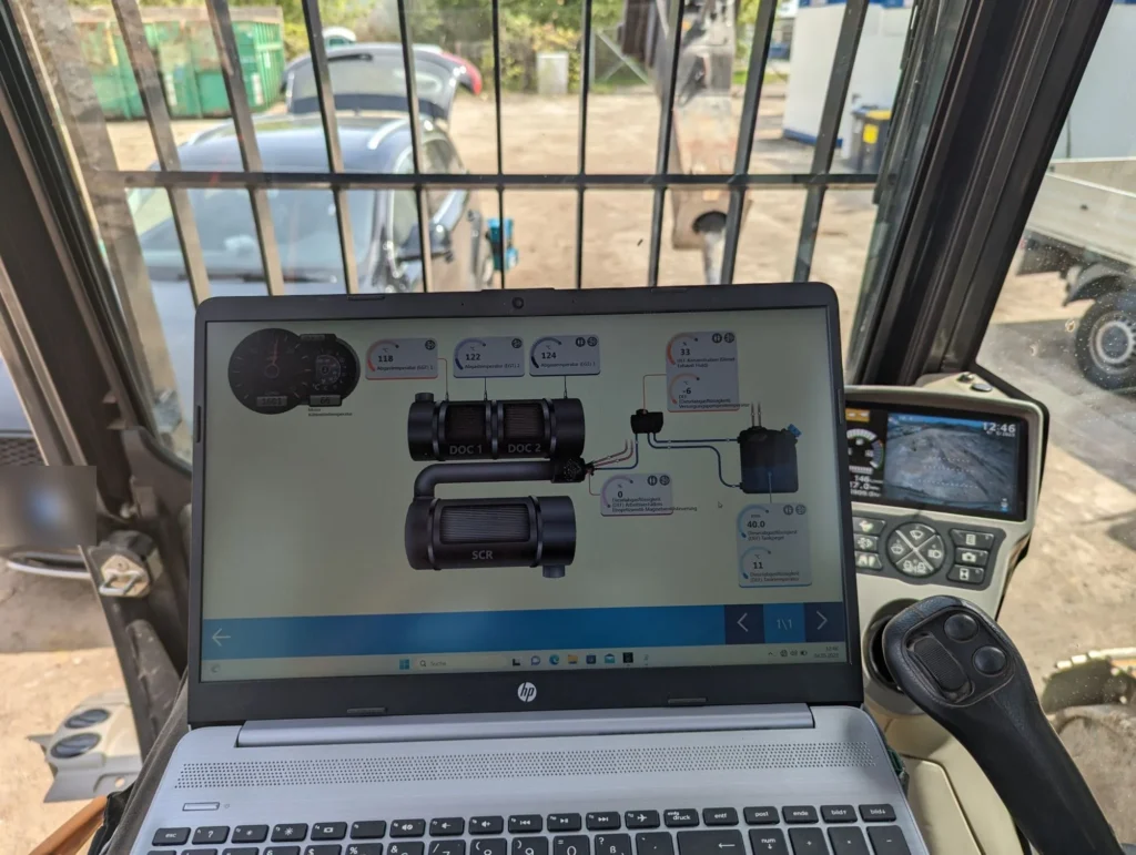 Fahrzeugdiagnose in der Kabine einer Baumaschine – Livedaten des AdBlue- und SCR-Systems auf dem Laptop