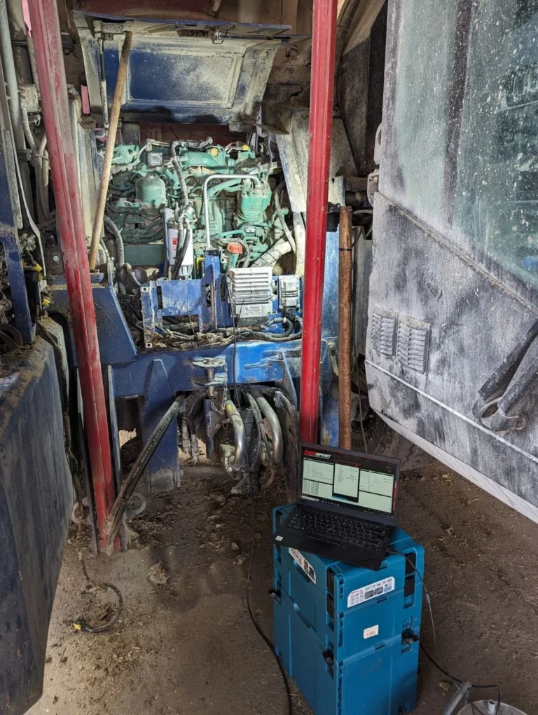 Vor-Ort-Service an einer Landmaschine mit Laptop am geöffneten Motorraum