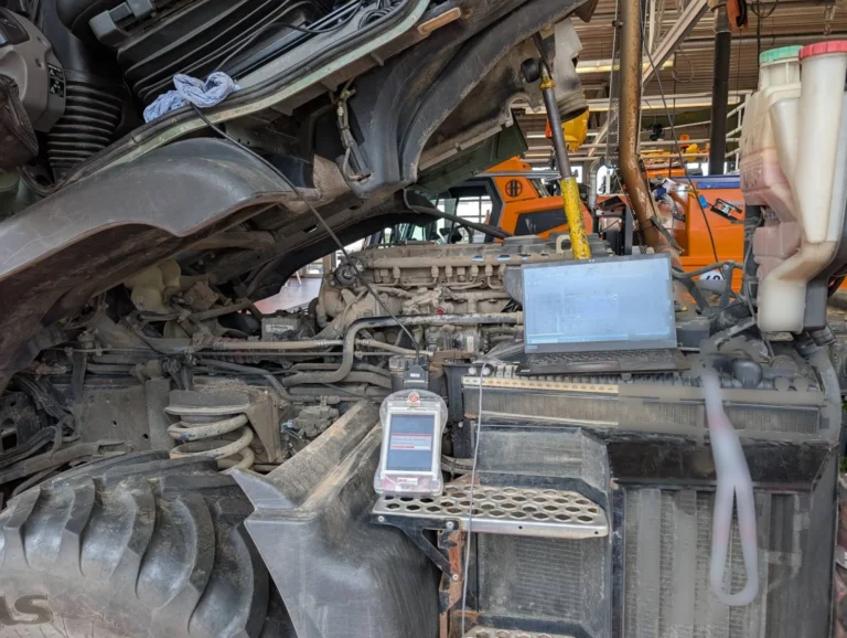 Vor-Ort-Service an einem Traktor mit Laptop und Programmiergerät am Motor